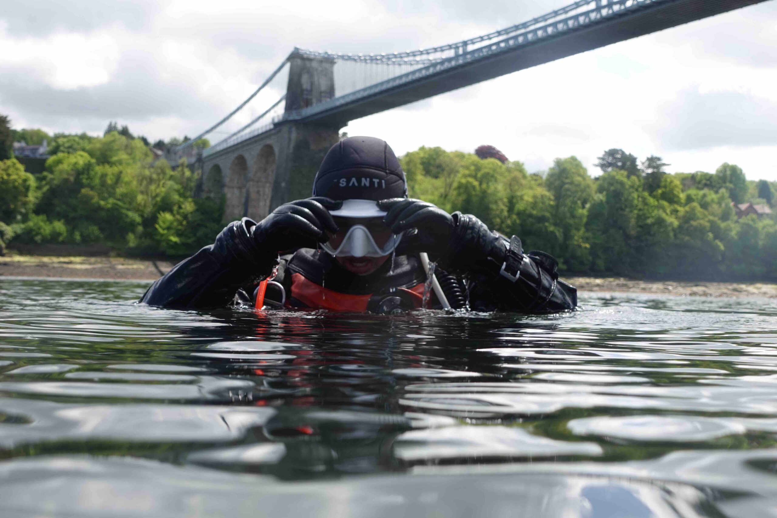 Scuba diver in the water placing mask on face.